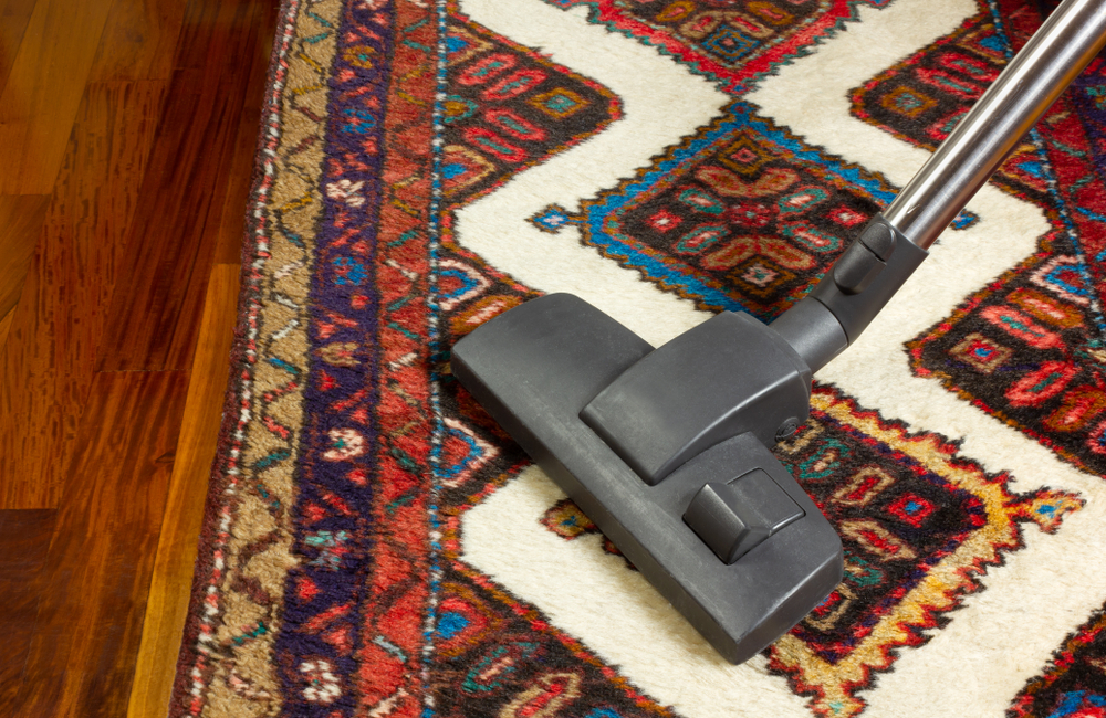 vacuuming patterened red white brown gold persian oriental rug to remove salt dirt and debris
